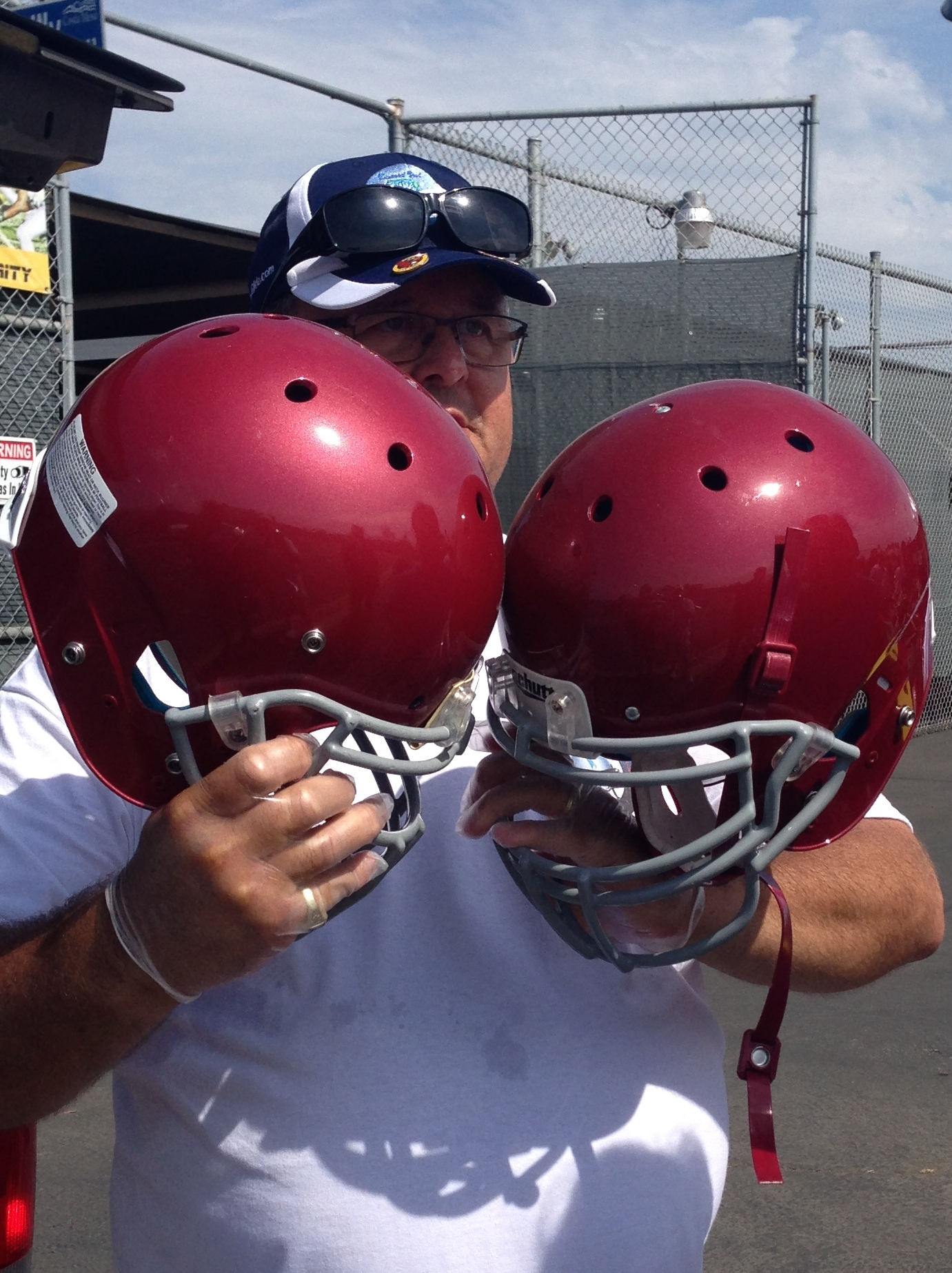 Diamond Seal Systems representative holding two treated Estancia High School football helmets